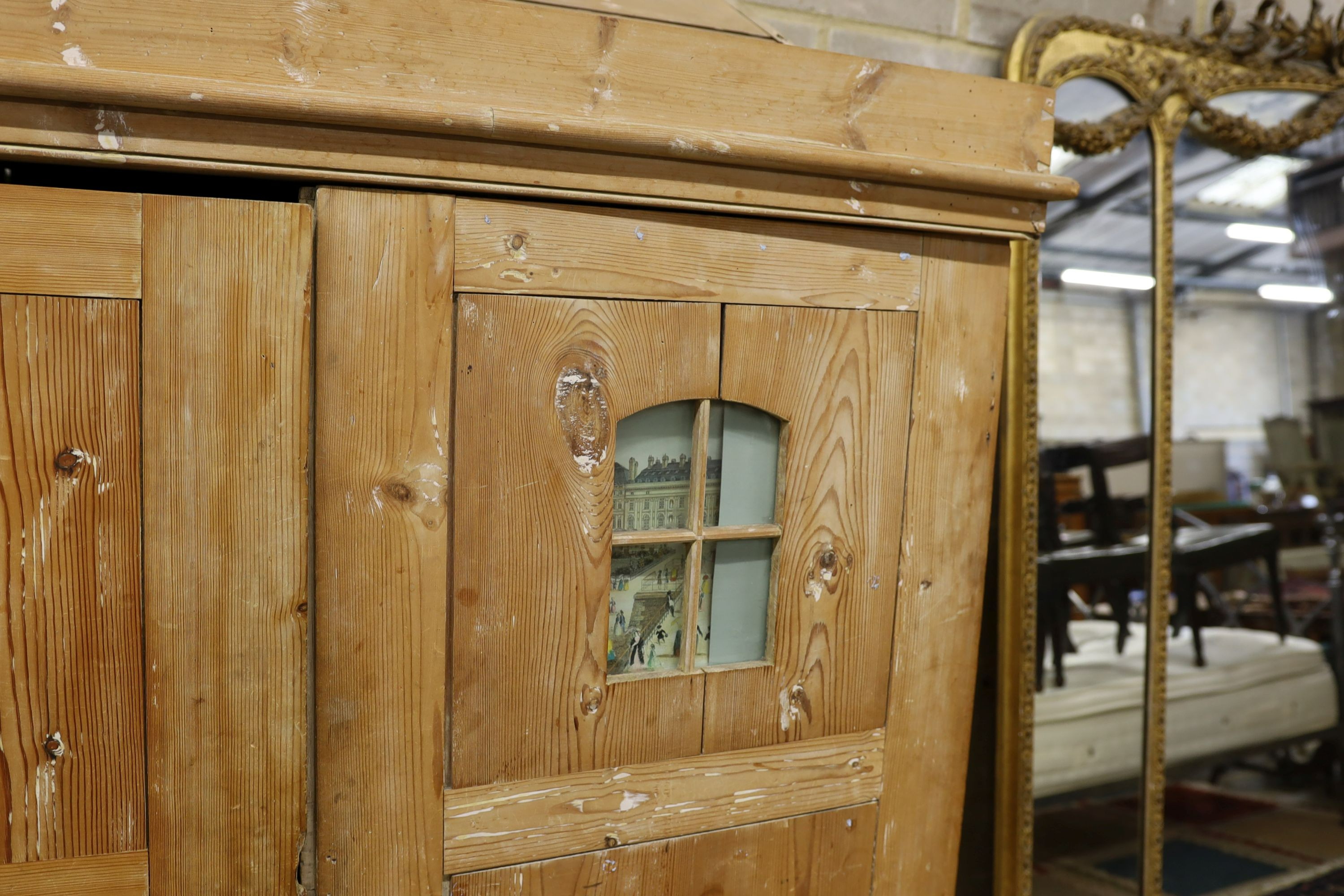 A 19th century stripped pine hall cupboard modelled as a dolls house the two door nine window facade enclosing a compartmented interior, width 182cm, depth 46cm, height 192cm